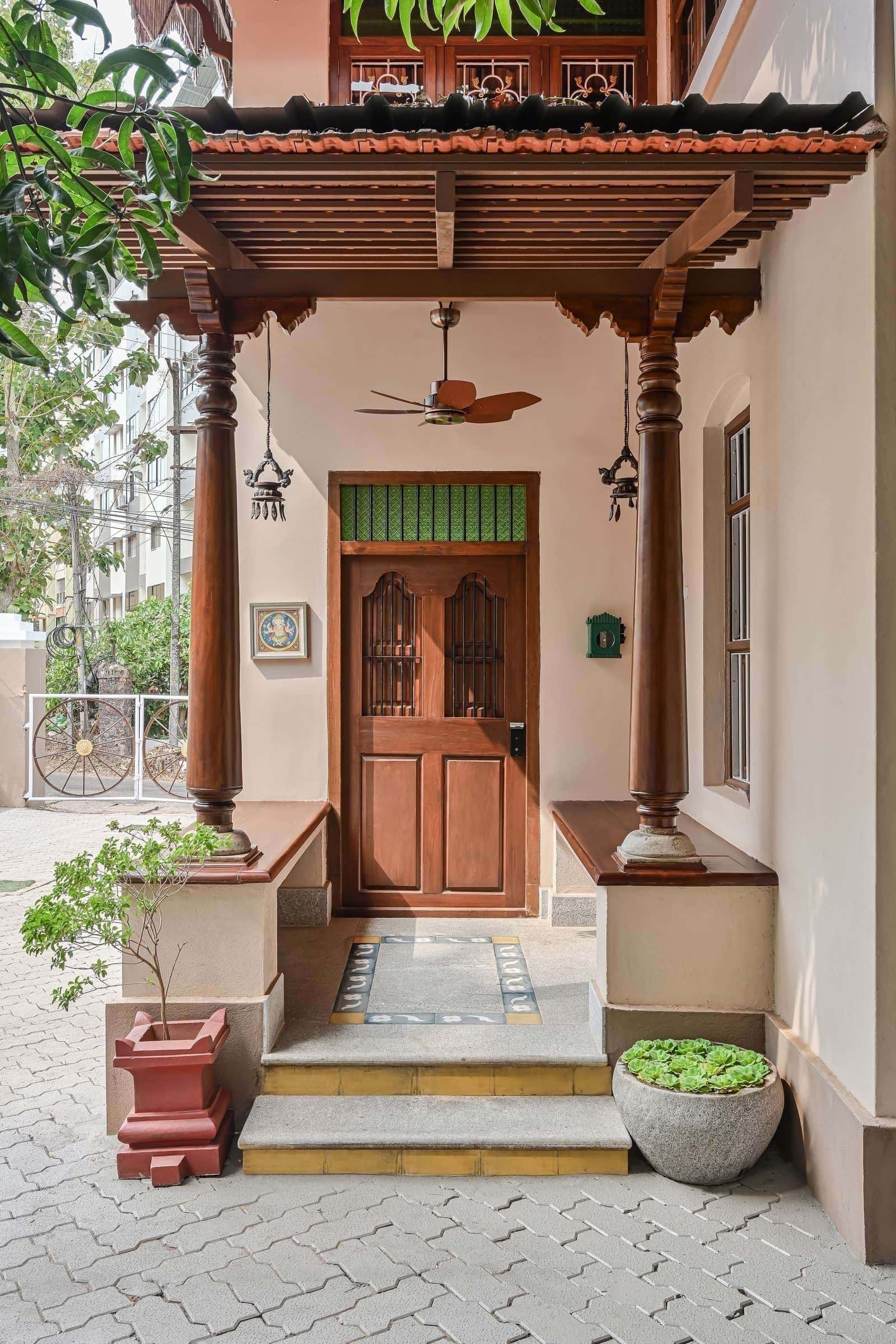 Traditional South Indian façade with tiled roof, shaded steps, and carved openings - an architectural threshold that mediates between the street and the home