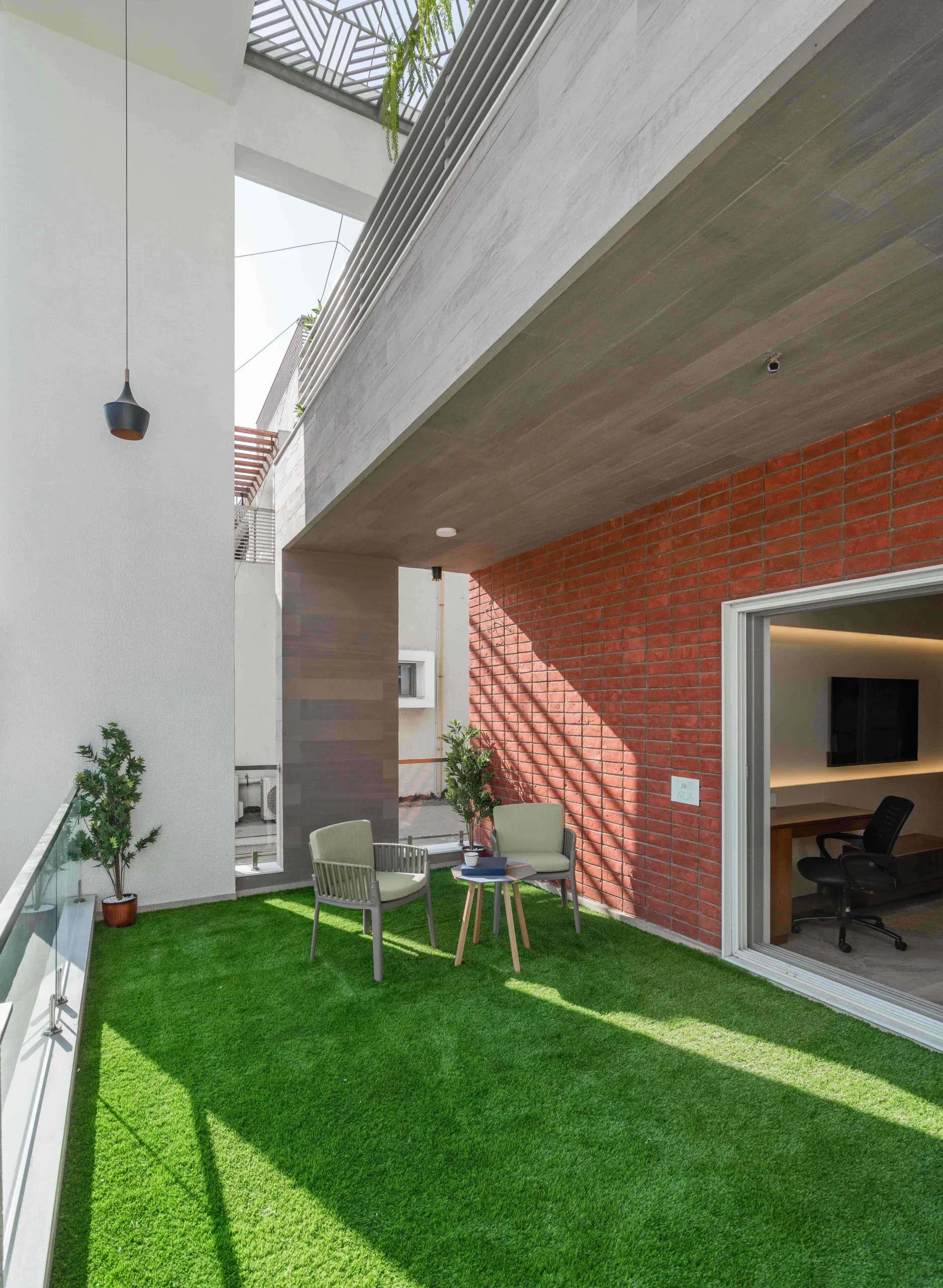 The elevated gardens on the south-east are created out of grey cubes clad with wooden figured MCM, while the walls are clad with brick cladding. A project by Prashant Parmar Architect