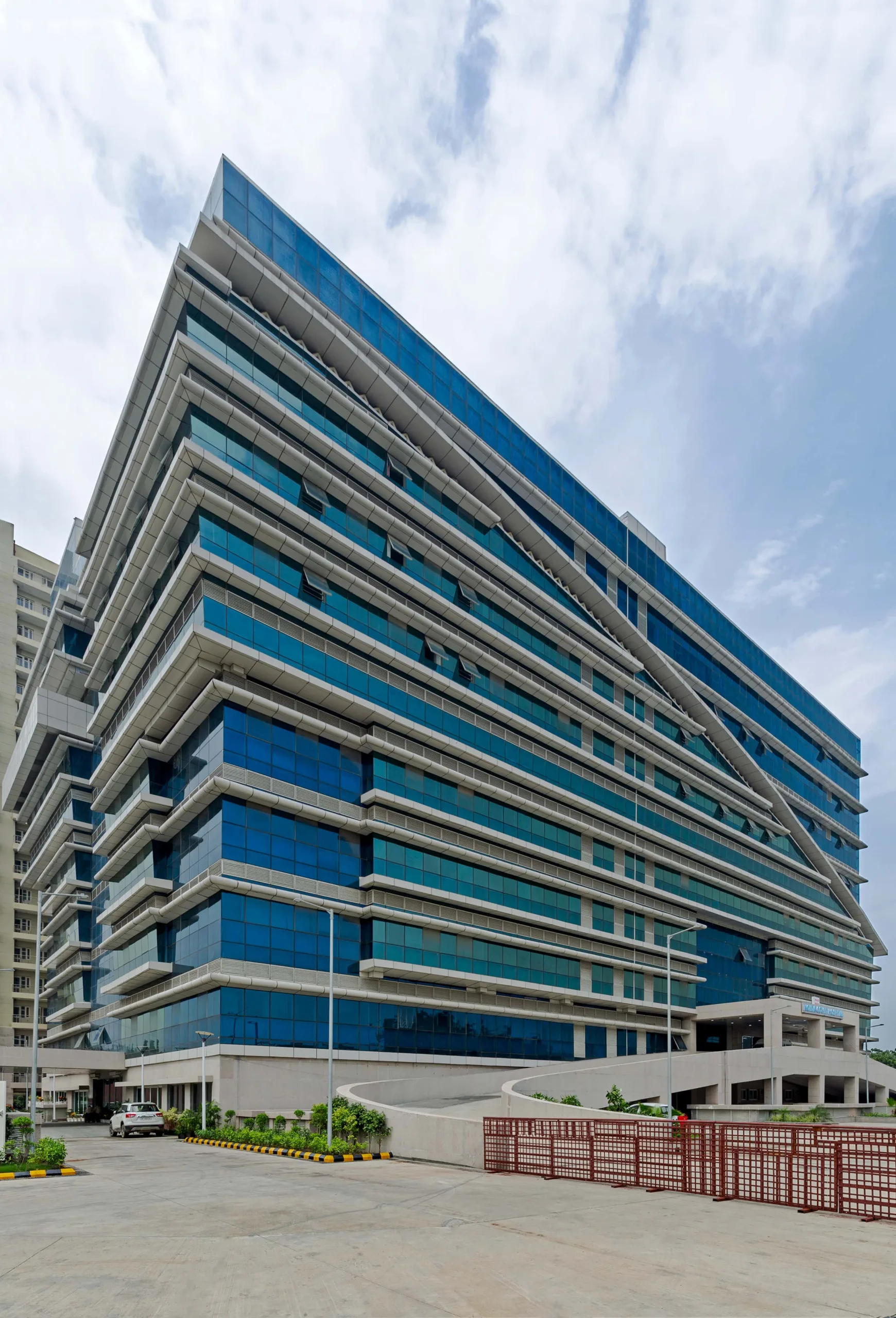 Layered healthcare envelope with recessed glazing and external horizontal shading devices, designed to moderate solar exposure and enhance indoor environmental comfort in a high-occupancy hospital setting. Project: Covid Hospital, Noida