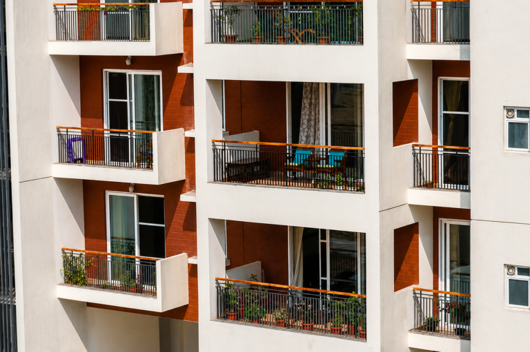 Deep balconies and chajjas wrap the residential perimeter, keeping habitable rooms a step back from direct solar exposure