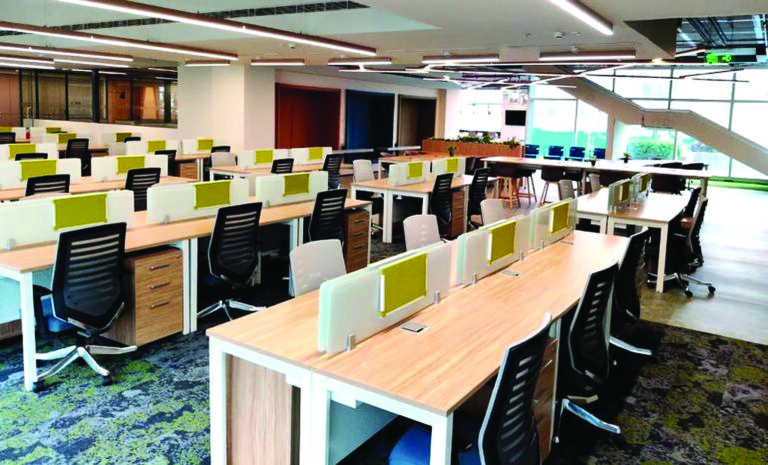 Deep daylight penetration inside the Bengaluru office, paired with IoT-controlled lighting holding the floor to 4–5 Wsq ft - a benchmark for a large-format office building