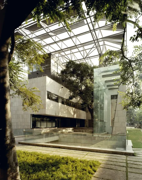 Front view of Alliance Française de Delhi, conceived as a composition of three distinct architectural layers: a dark stone-clad ground-floor plinth, a Dholpur stone-clad building body, and a large rooftop pergola that shades the building and creates comfortable outdoor spaces (Image Credit - ABRD)
