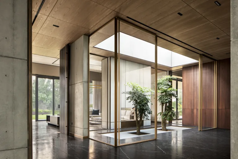 House of Sunwells, Punjab - Full-height glazing at the entrance sequence is framed in timber, with a coffered timber ceiling extending the threshold’s material language from exterior to interior (Image Credit - Habitat Architects)