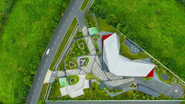 Aerial Site Context: The aerial view reveals the triangular site, landscaped arrival sequence, and boomerang-shaped building that responds to the site’s geometry and future urban context