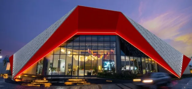 The completed sales experience centre in Moradabad. The folded aluminium envelope, transparent glazed façade, and integrated architectural lighting establish a bold architectural identity, transforming the building into the first physical expression of the township’s vision.