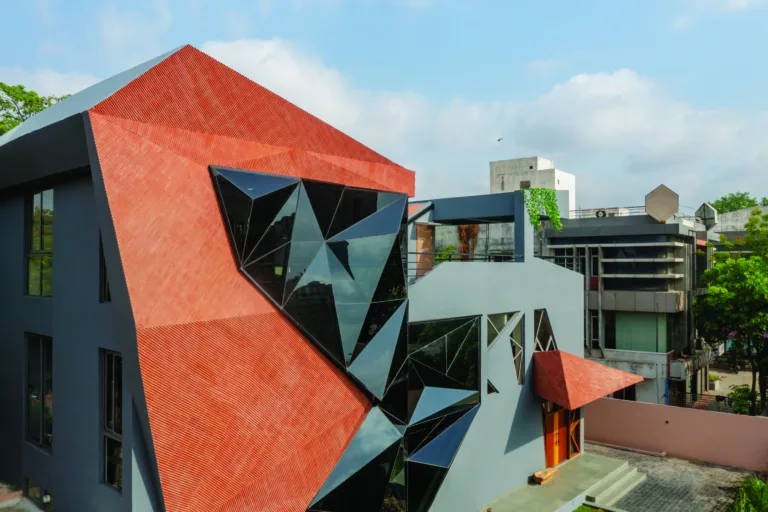The project features a geometric, faceted design that integrates angular glass elements and terracotta-like tiles